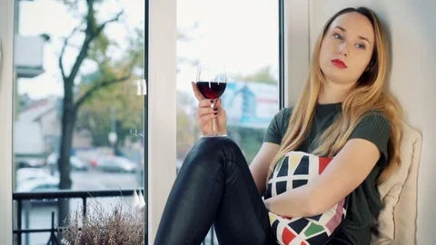 Sad girl drinking wine by the window and thinking about her problems Stock Footage 70409785