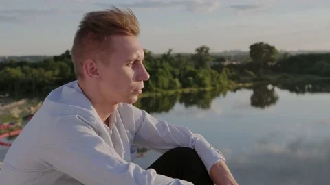 Sad guy against the backdrop of forest and river. Profile. Slow motion. Closeup Stock Footage 135669214