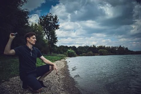 Sad guy on the beach throwing away his black mask Stockfoto's