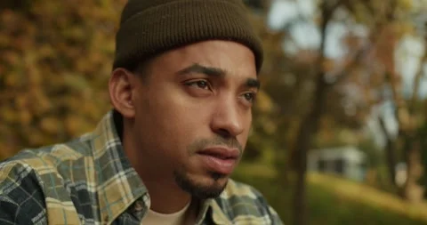 A sad guy with Black skin and stubble sits and looks thoughtfully to the side Stock Footage 299925045
