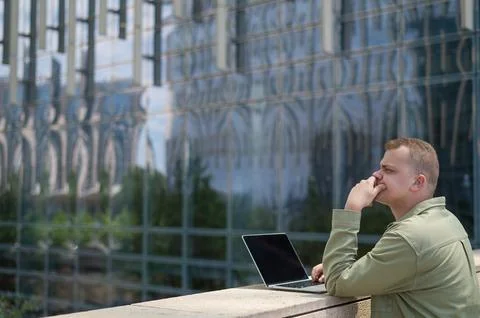 Sad guy with hearing aid using laptop outdoors. Stock-Fotos