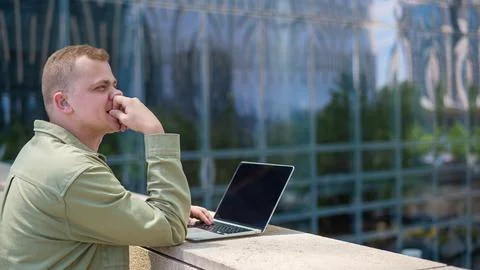 Sad guy with hearing aid using laptop outdoors. Stock-Fotos