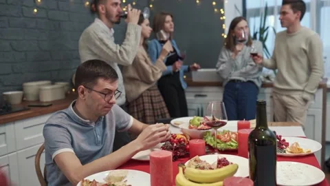 Sad guy with stressed face is sitting alone while cheerful friends are having Vidéo 151622947