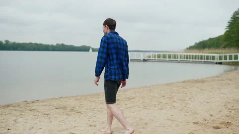 A sad guy walks along the beach and falls to his knees Stock Footage 196148451
