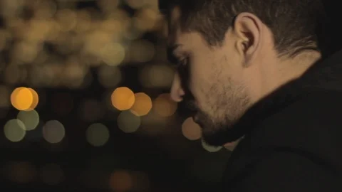 Sad handsome man with beard and brown hair leaning on a railing of the bridge, Stock Footage 110914401
