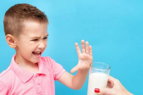 Sad harmful little kid refusing to drink milk showing stop gesture Stock Photos