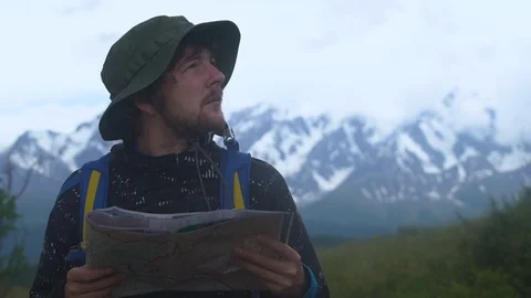 Sad hipster young man with backpack holding in hands and looking on map of foggy Video stock 93170785
