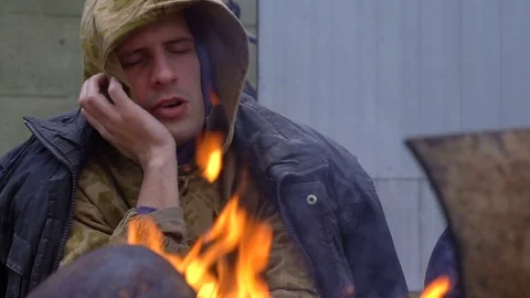 Sad homeless by the fire closeup Stockbeeldmateriaal 82700257