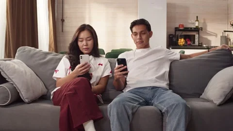Sad ignore couple sit couch at home using cell phone. Addiction social media. Stock Footage 327198095