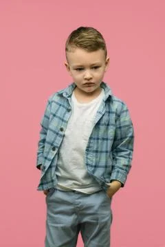 Sad kid posing on pink background. Vertical photo. Stock Photos