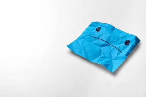 Sad light blue paper face on a white background. Blue Monday concept Stock Photos