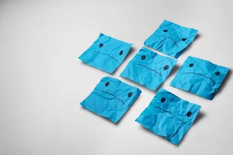 Sad light blue paper faces on a white background. Blue Monday concept. Stock Photos