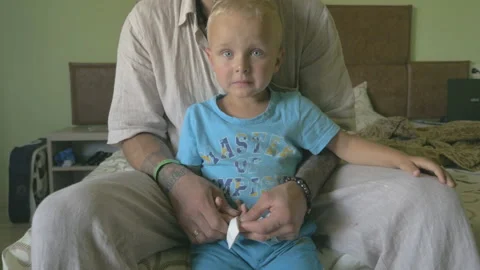 Sad little boy crying because of injury. Dad comforting him. Video stock 96606776