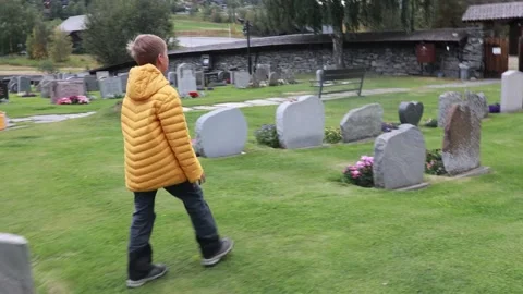 Sad little child, blond boy, standing in the rain on cemetery, sad person, .. Stock Footage 343642017