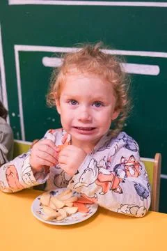 Sad little child crying while eating healthy snack. Frustrated blonde girl Stock Photos