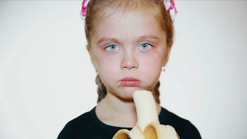 sad little girl eats a banana Stock Video Pond5