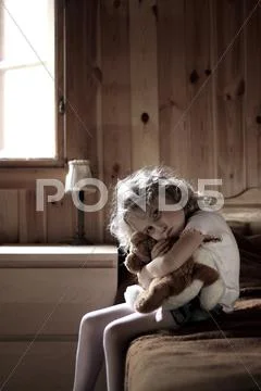 Sad little girl hugging teddy bear Stock Photos
