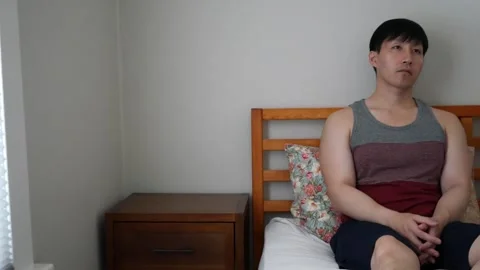 Sad lonely Asian man staring at the wall on his bed Stock Footage 248665553