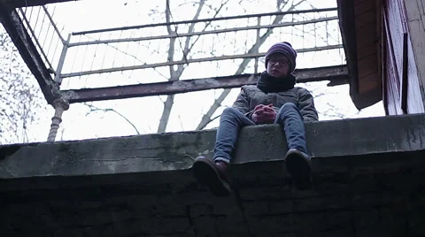 Sad lonely boy sitting alone on edge of abandoned roof, transitional age crisis Stock Footage 62589251