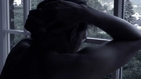 Sad lonely man looking out of window in mountains back shot desaturated Stock Footage 76628368