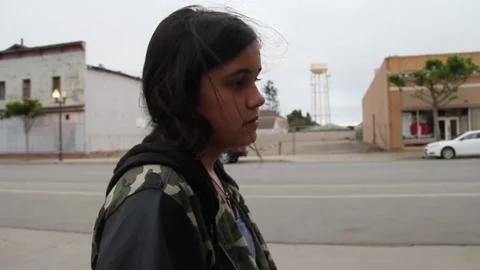 Sad looking non binary kid stares blankly while standing around in town Stock Footage 155491759