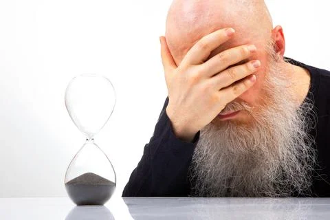 Sad man with a big white beard covered his face with his hand in regret at .. Stock Photos
