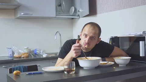 Sad man eating pasta at the table. Home in his kitchen. He worries because of Video stock 101366188