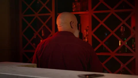 Sad man in his 50s pouring liquor into glass at home bar, alcohol addiction Stock Footage 346714109