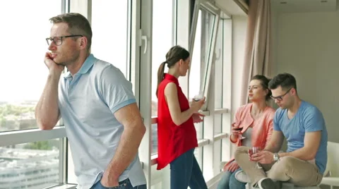 Sad man looking out the window while his friends chatting Stock-Footage 50564930