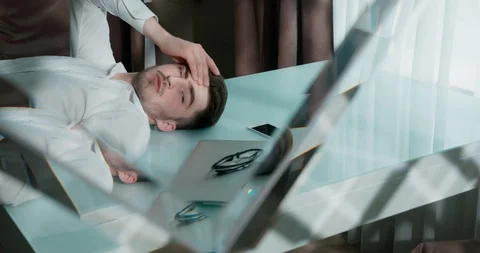 Sad man lying on the table with laptop, smartphone and glasses. He closes his Stock Footage 120512347