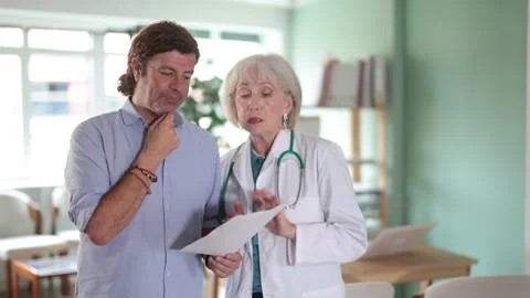 Sad man patient with documents discuss treatment with senior female doctor Stock Footage 345513971