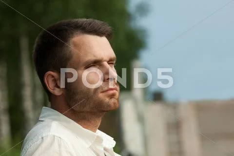 Sad man portrait in summer park look at sunset Stock Photos