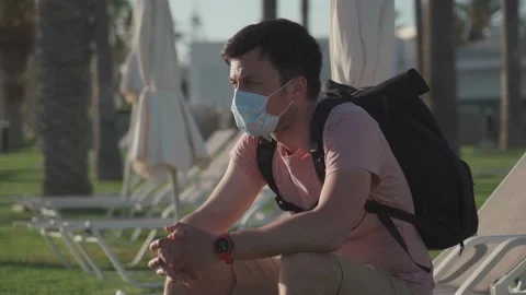 Sad man in protective mask sits on lounger in empty hotel in Cyprus during Stock Footage 166814633