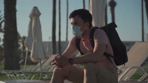 Sad man in protective mask sits on lounger in empty hotel in Cyprus during Stock Footage 166814648