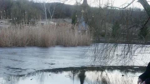 A sad man seeks peace on the river bank opposite the monastery the concept o 库存影片 170277796