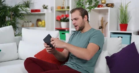 Sad Man Sit on Sofa Play Games on Digital Tablet and Lose Disappointed Activity Stock Footage 87897108