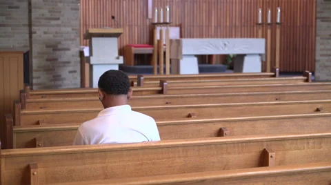 Sad man sits alone praying in a church Stock Footage 67383615
