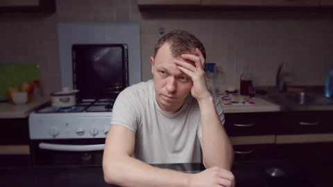 Sad man sits in the evening at the kitchen, immersed in his problems Stock Footage 134884356