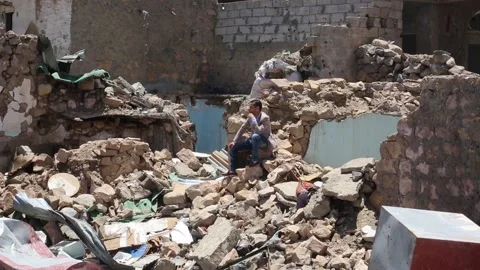 A sad man sits on the rubble of a destroyed house Stock Footage 148658742