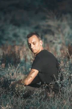 Sad man sitting alone in an empty field Stock Photos