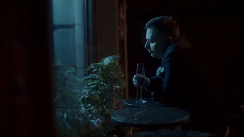 A sad man sitting alone at the table and drinking Video stock 258331061