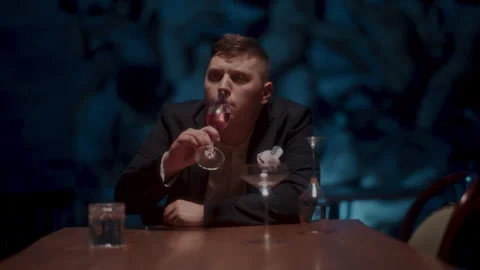 A sad man sitting alone at the table and holding a glass of wine Stock-Footage 258335080