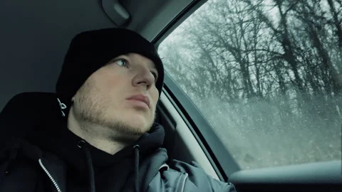 Sad man sitting in a car, a young guy looking out the window from the car. Vídeos de archivo 263674656