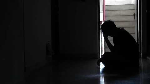 Sad man sitting in the dark leaning against the wall in old condo Stock Footage 140774798