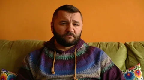 Sad man sitting on sofa at home and thinking about something Stock Footage 61302981