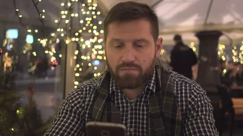Sad man sms typing by smartphone app, at night, in cafe, steadycam shot 库存影片 72782308