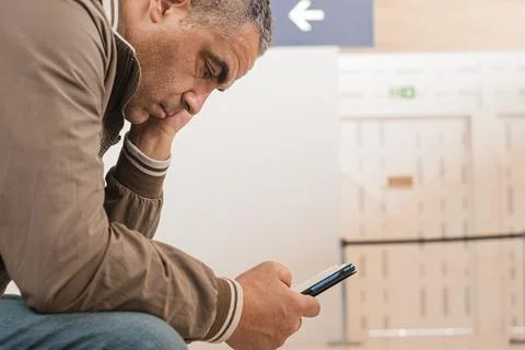 Sad man waiting for delayed flight in airport. Traveler worrying something Stock Photos