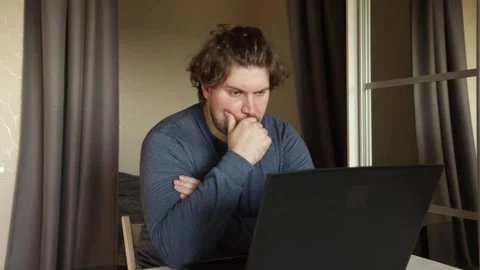 Sad man working on laptop, dealing with stress from an online job, showing .. Stock Footage 311755428