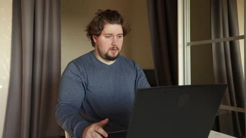 Sad man working on laptop, expressing emotion over a failed project, sittin.. Stock Footage 307098761