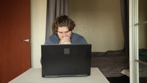 Sad man working on laptop, typing in a modern home office, struggling with .. Stock Footage 305388788